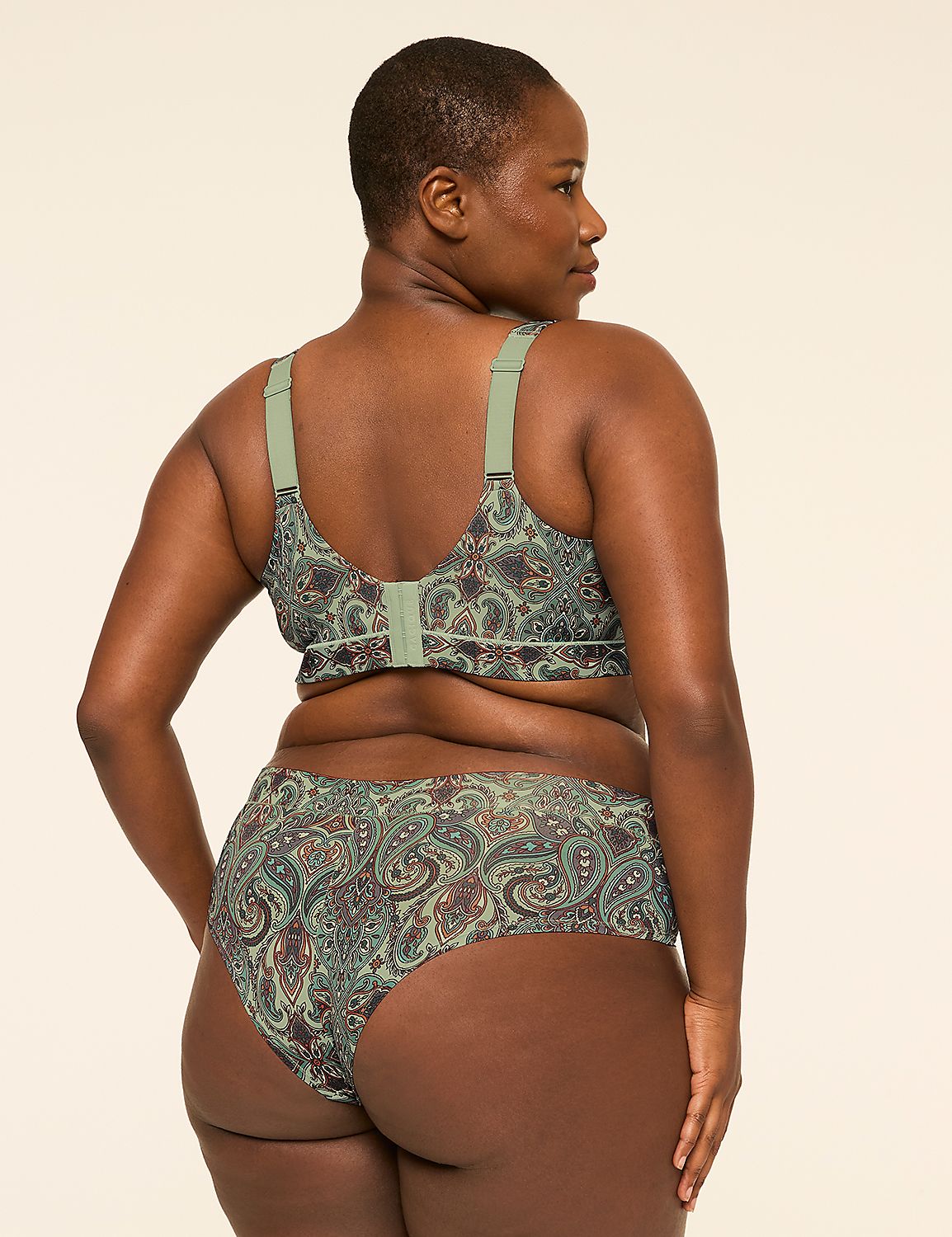 A woman with dark skin and short hair, wearing a green paisley-patterned bra and underwear, stands against a plain, light-colored background. Product Image 2