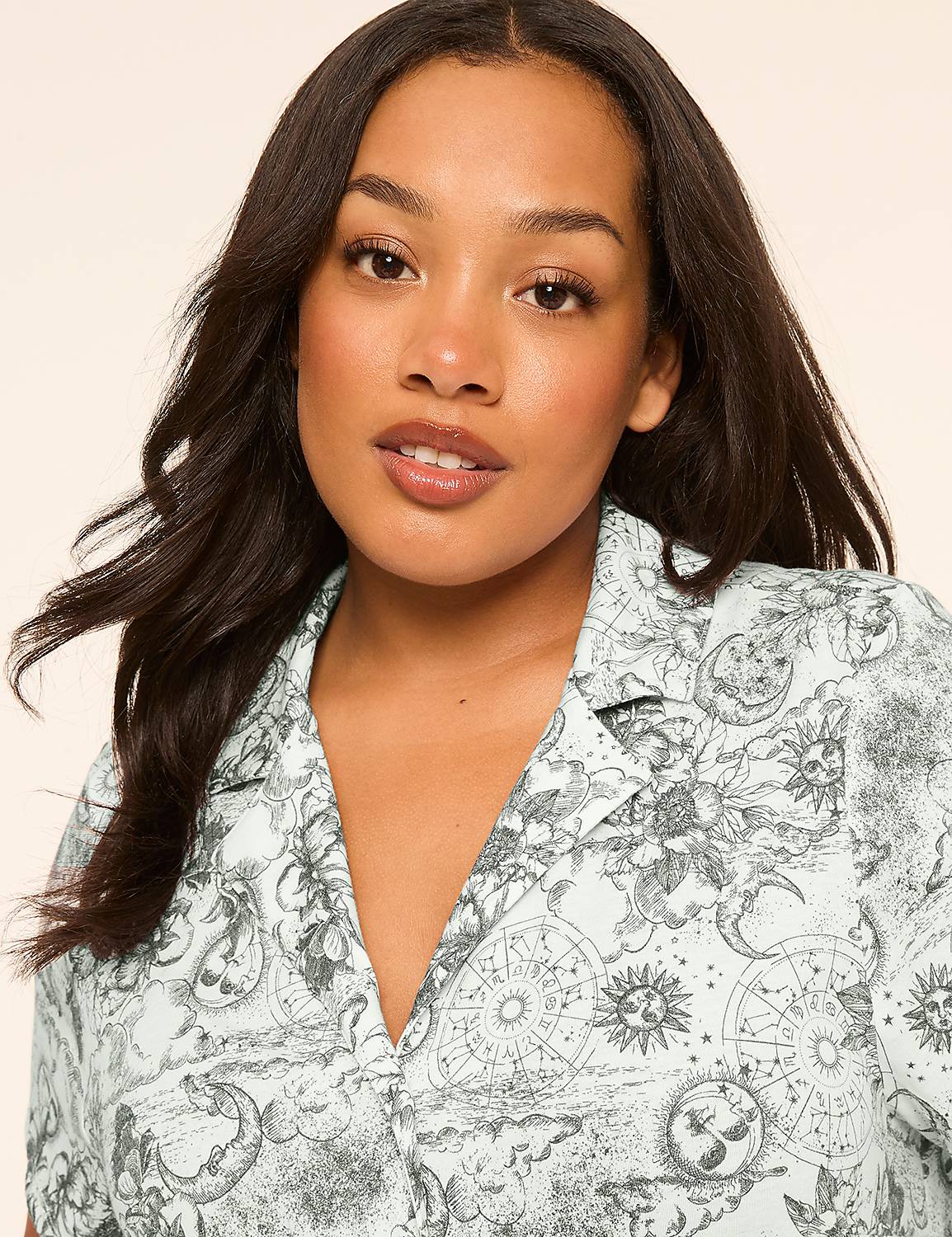 A young woman with dark hair and a light complexion looks forward, wearing a light blue collared shirt with a celestial print against a plain, light background. Product Image 4