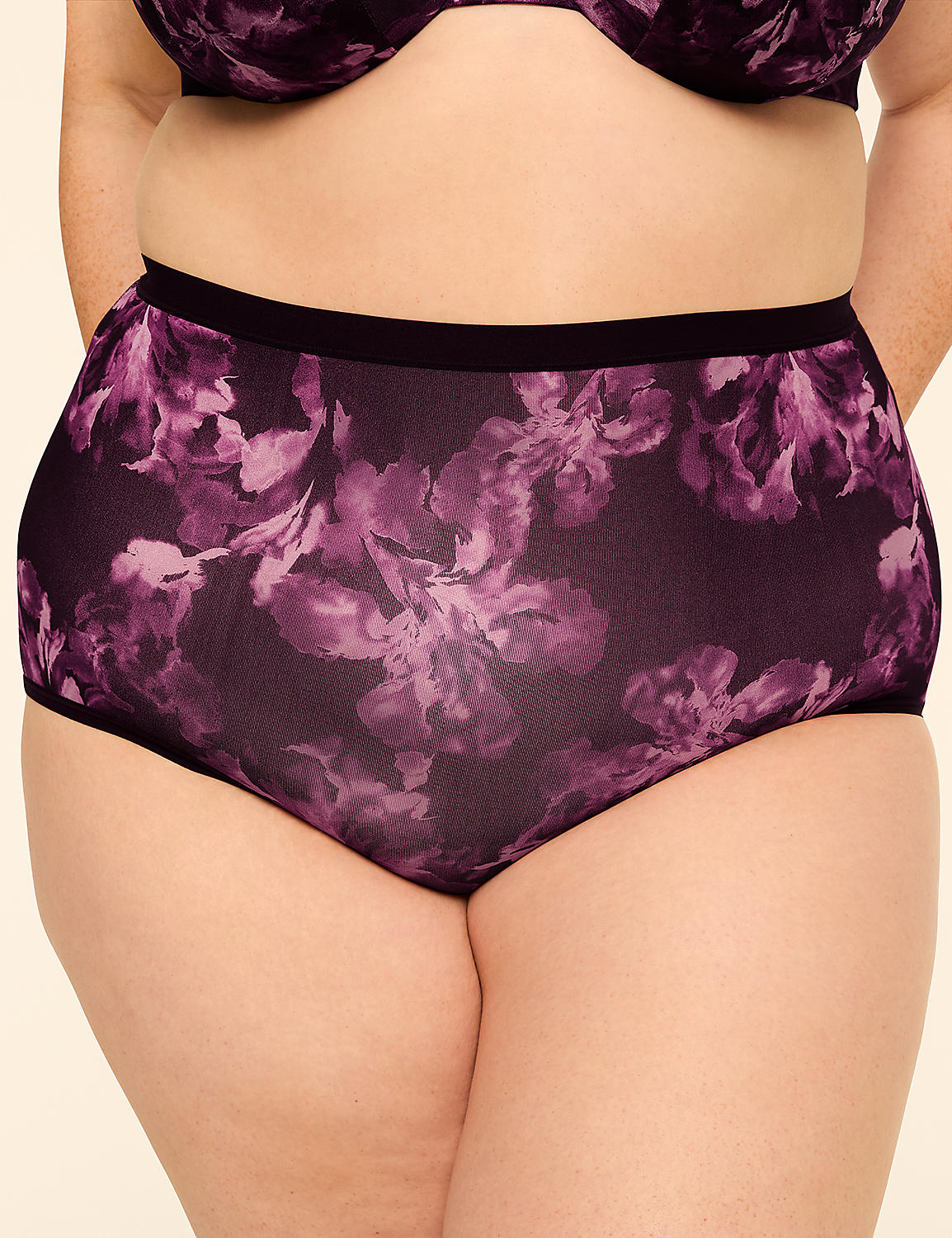A person wears high-waisted purple floral underwear in the foreground, with a plain beige background. Product Image 1
