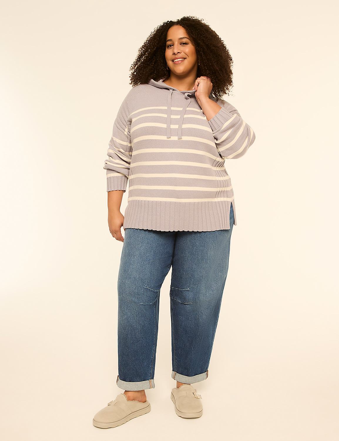 A smiling woman with curly hair stands in the foreground wearing a striped sweater and jeans, against a plain, light-colored background. Product Image 3