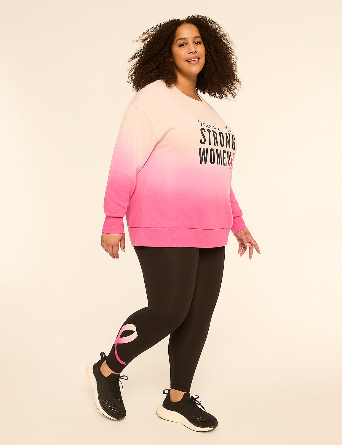 A woman in a pink ombre sweatshirt and black leggings with a pink ribbon design on the leg poses against a plain, light background. Product Image 3