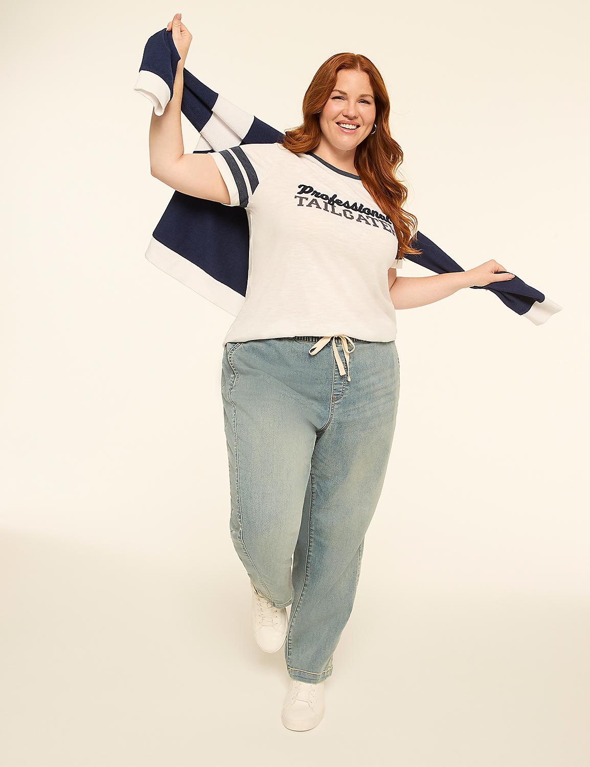 A smiling woman with red hair in a white t-shirt and jeans holds a striped scarf over her shoulder against a plain cream background. Product Image 3