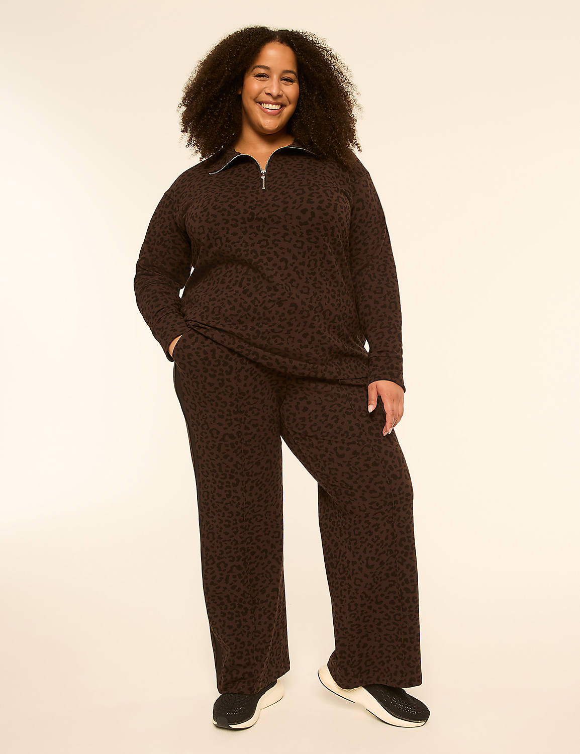 A smiling woman in a leopard-print loungewear set stands against a plain, light-colored background. Product Image 3
