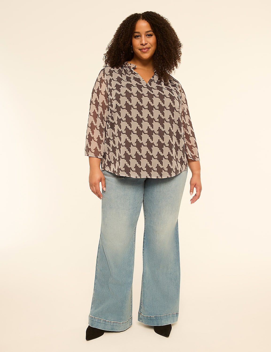 A woman with curly hair stands in the foreground wearing a patterned blouse and wide-leg jeans against a plain, light-colored background. Product Image 4