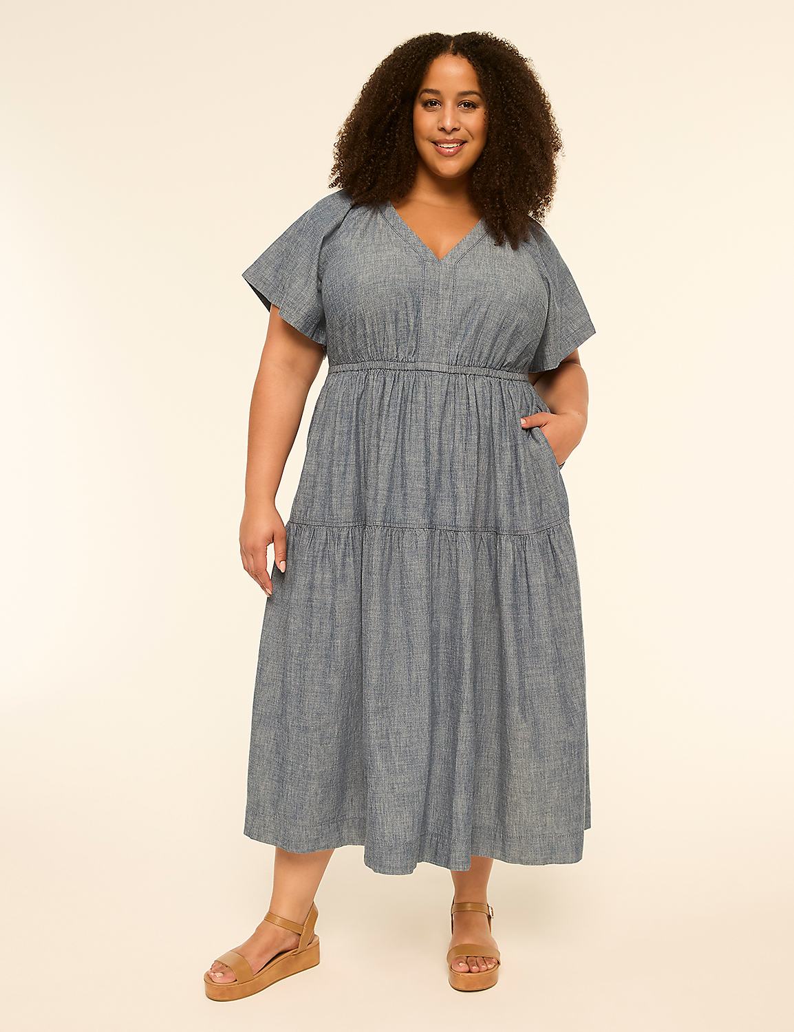 A smiling woman in a blue tiered dress stands against a plain, light-colored background. Product Image 1