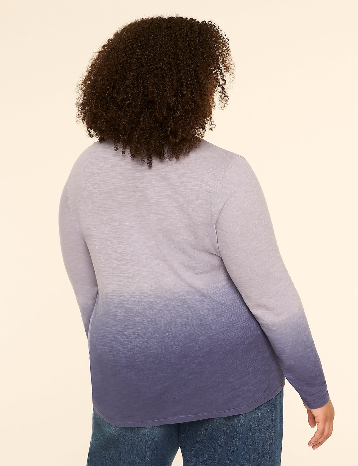 A woman with curly brown hair, seen from the back, wears a long-sleeved shirt with a purple to blue ombre gradient and blue jeans against a plain beige background. Product Image 2