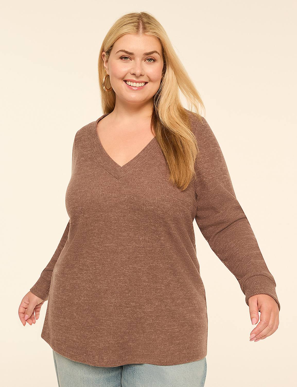 A smiling woman with blonde hair and a v-neck sweater stands against a plain, light-colored background. Product Image 1