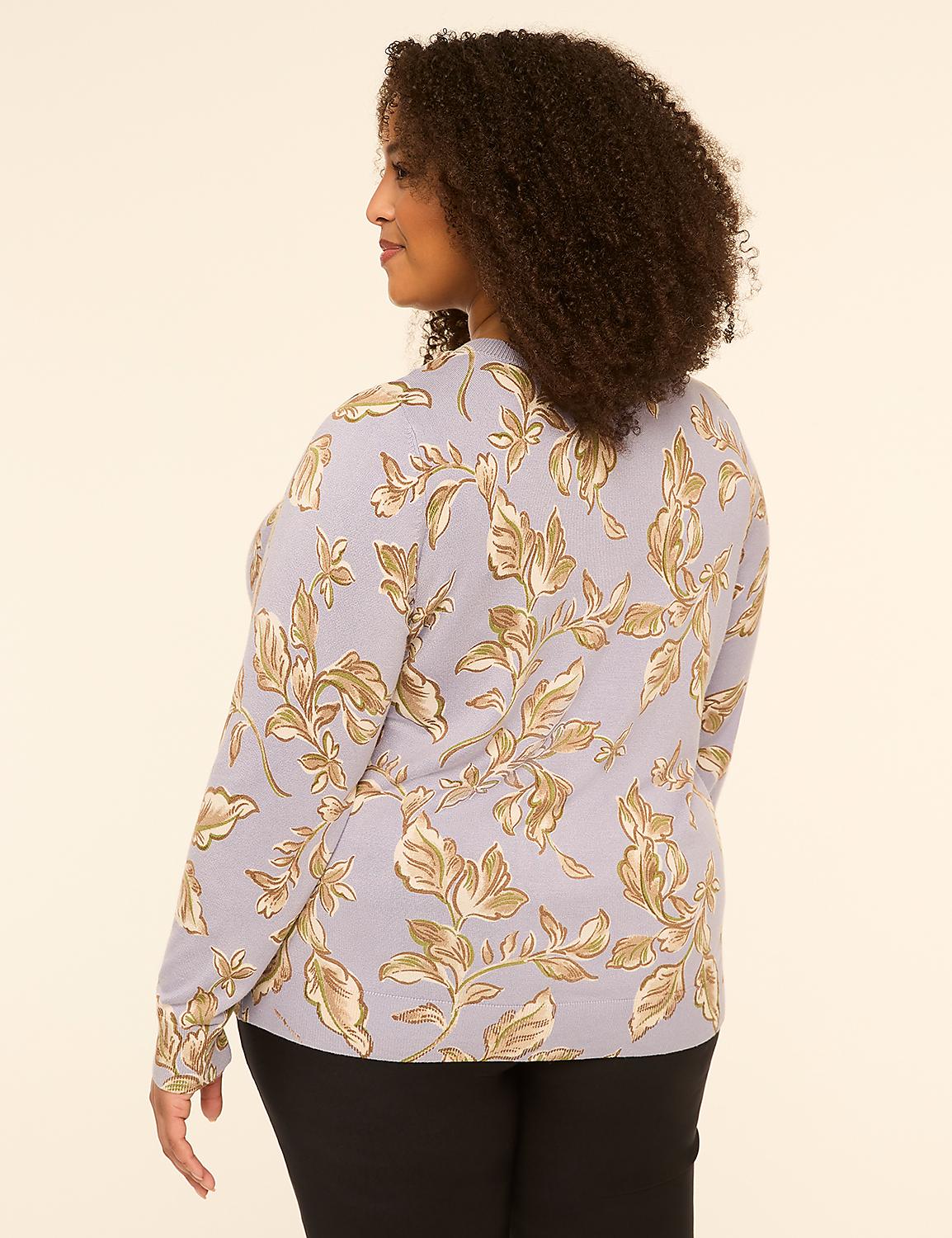 A woman with curly brown hair, wearing a light purple floral-patterned sweater and black pants, stands against a plain beige background. Product Image 2