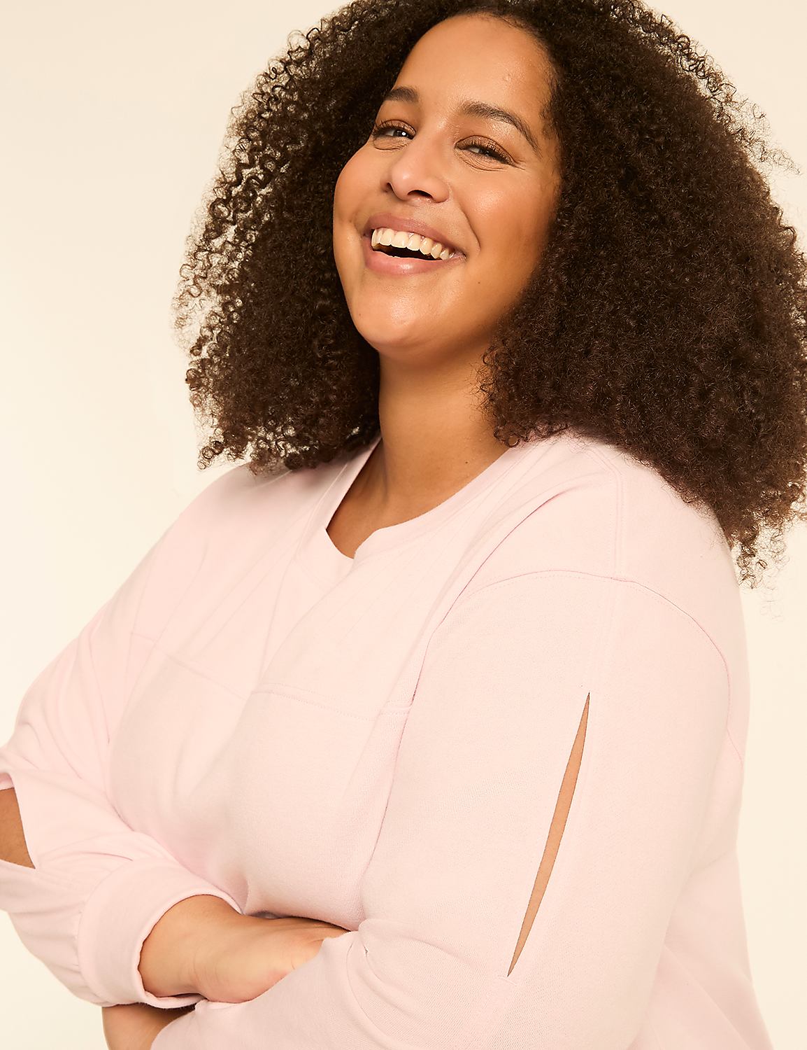 A smiling woman with curly hair in a light pink top poses against a plain, light-colored background. Product Image 4