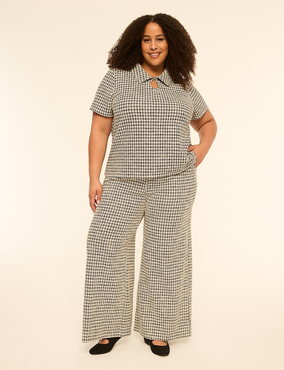 A smiling woman with curly hair stands in a patterned outfit against a plain, light-colored background. Product Image 3