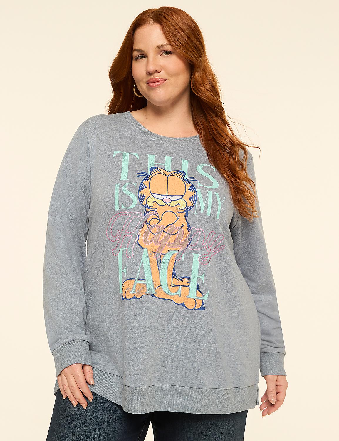 A woman with red hair stands in front of a plain, light-colored background, wearing a blue sweatshirt with a Garfield graphic. Product Image 1
