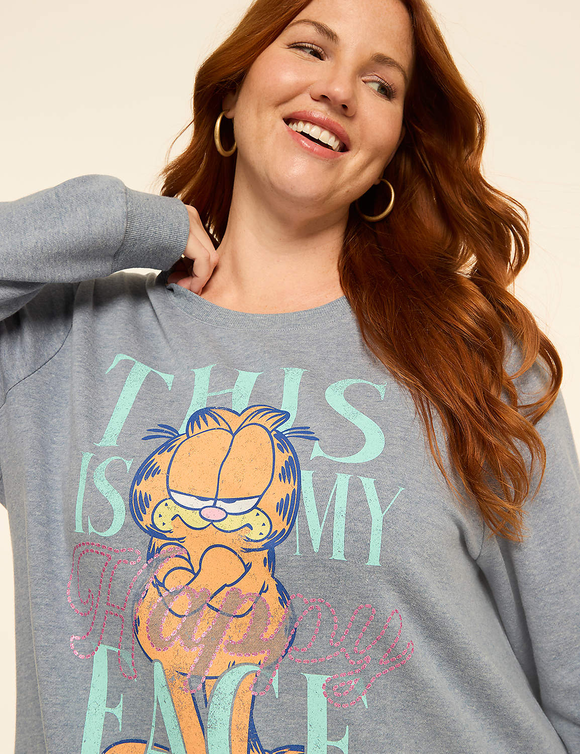 A smiling woman with red hair wears a gray sweatshirt with a Garfield graphic and text, against a plain beige background. Product Image 4