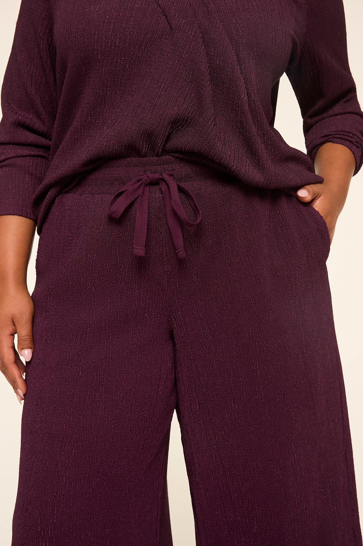 A person in a plum-colored ribbed loungewear set with a drawstring waist stands against a plain, light-colored background. Product Image 8