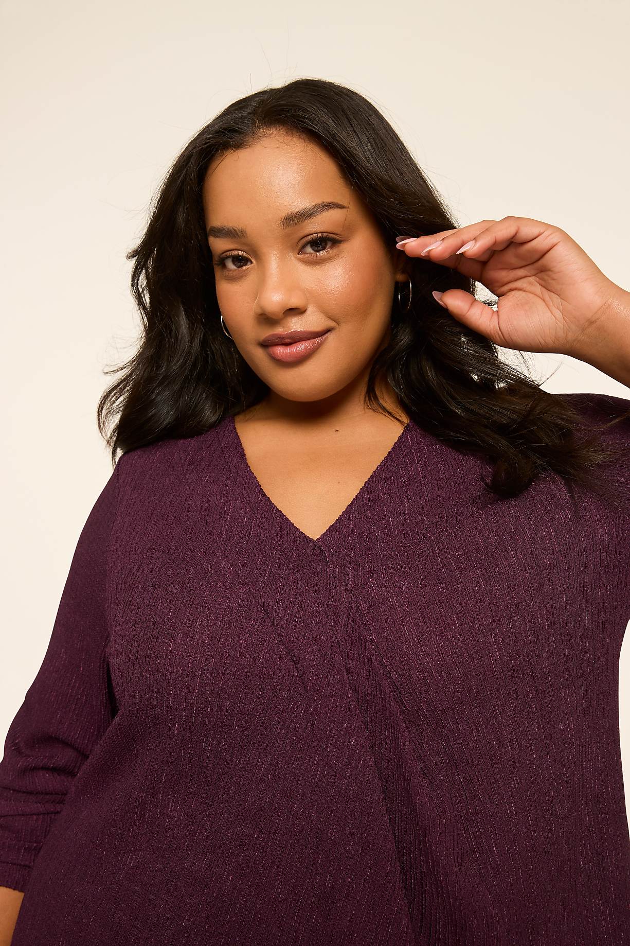 A woman with dark hair and a purple top poses against a plain, light-colored background. Product Image 9