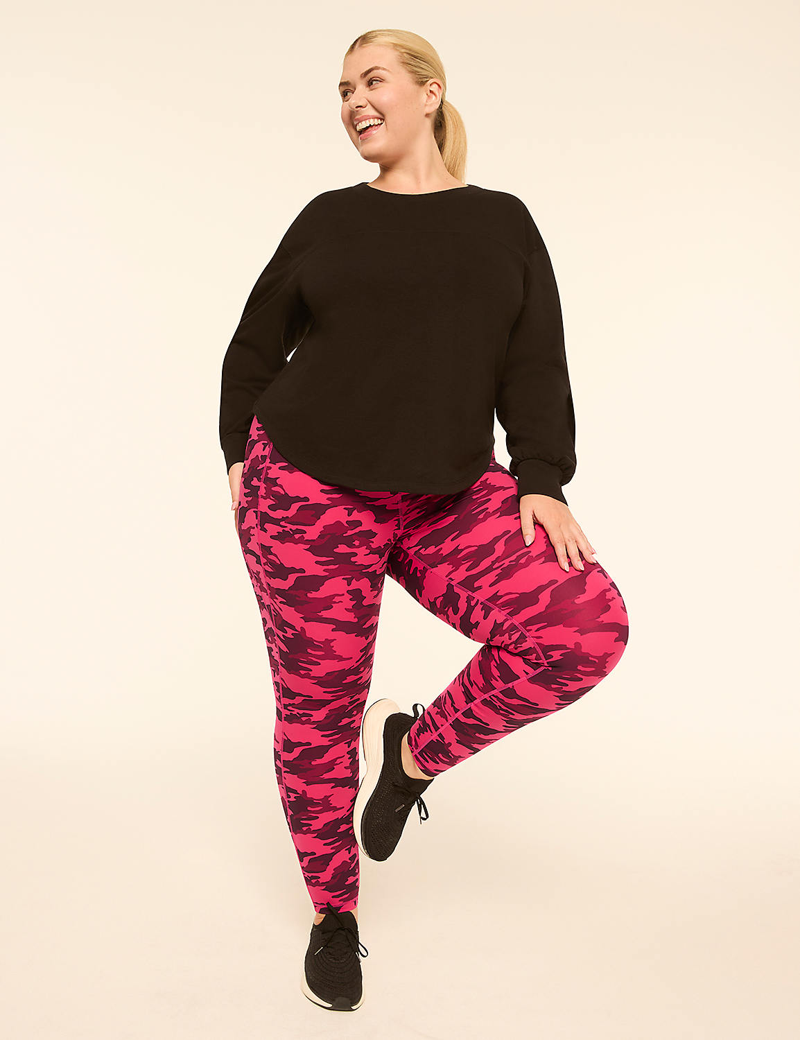 A woman in a black top and pink patterned leggings stands on one leg against a plain, light-colored background. Product Image 3