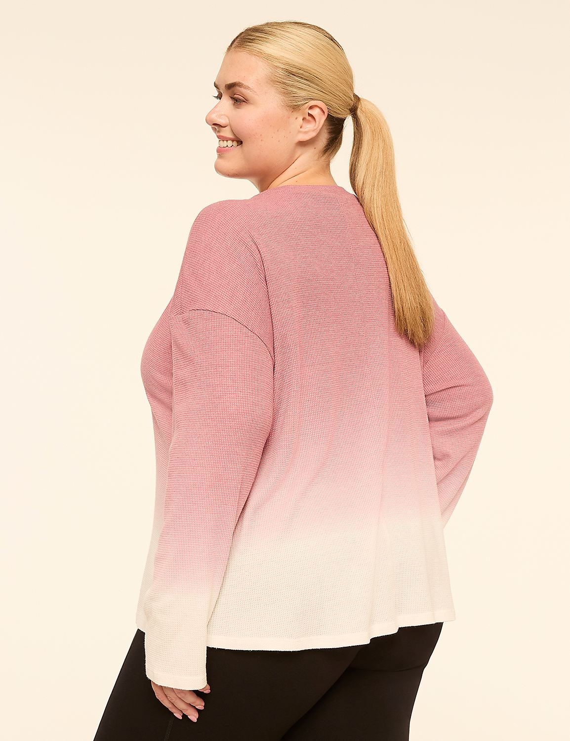 A woman in a pink and white ombre sweater and black leggings stands against a plain, light-colored background. Product Image 2