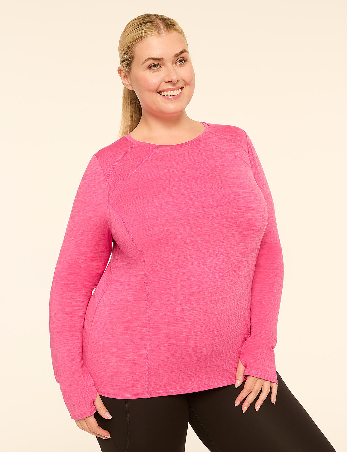 A smiling woman in a pink long-sleeved shirt and black leggings stands against a plain, light-colored background. Product Image 1