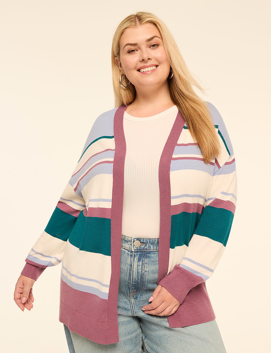 A smiling woman with blonde hair wears a striped cardigan over a white top and jeans, with a plain, light-colored background. Product Image 1