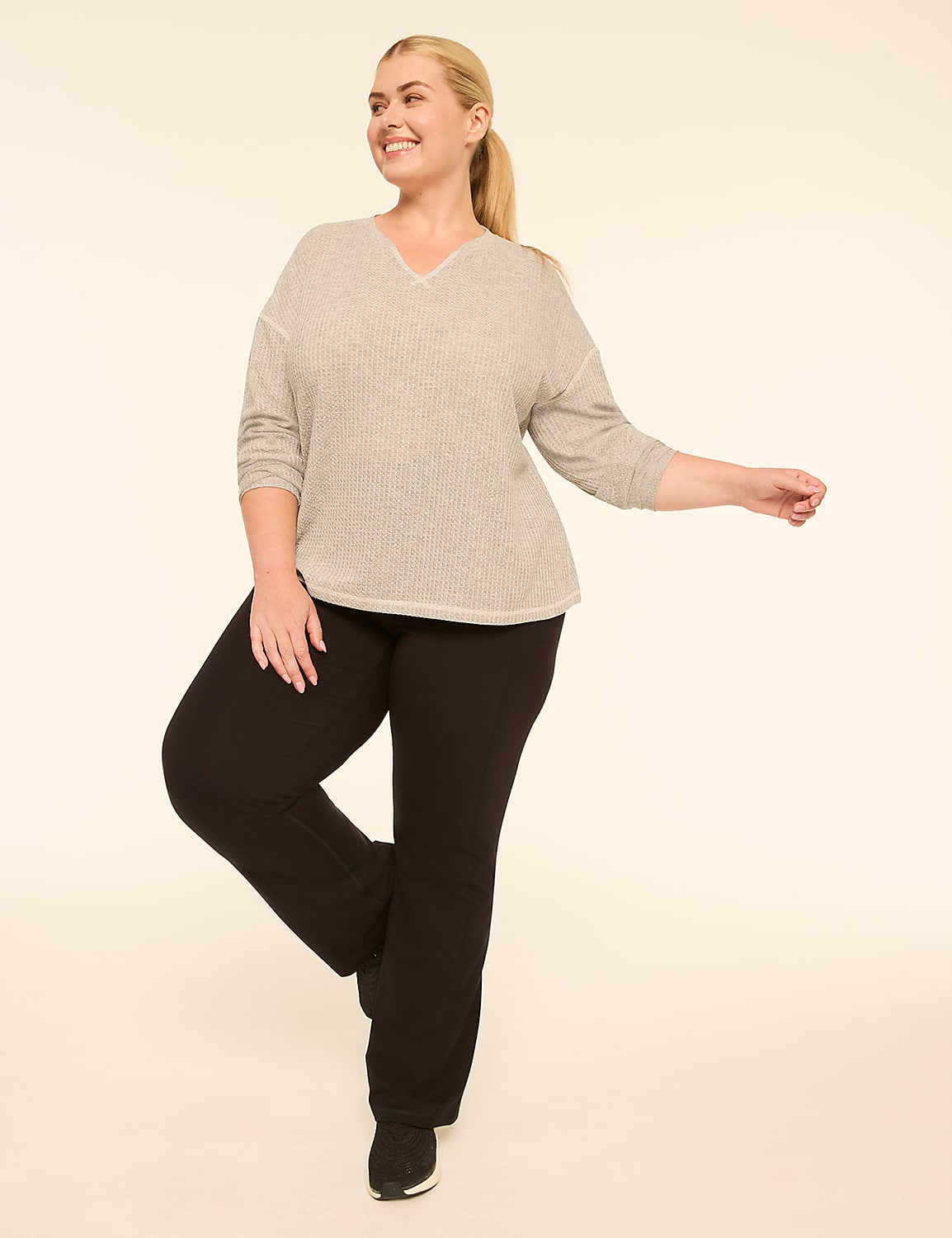 A woman in a gray v-neck sweater and black pants stands on one leg against a plain, light-colored background. Product Image 3
