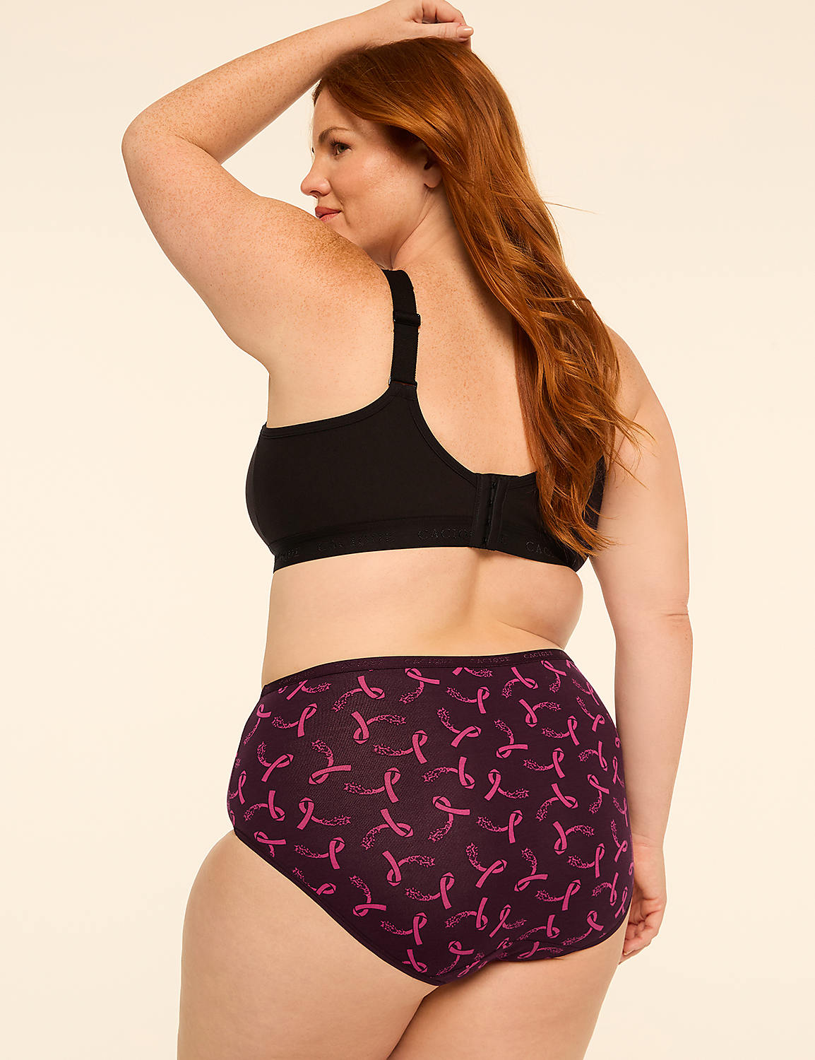 A woman with red hair in a black bra and purple patterned underwear stands against a plain beige background. Product Image 2