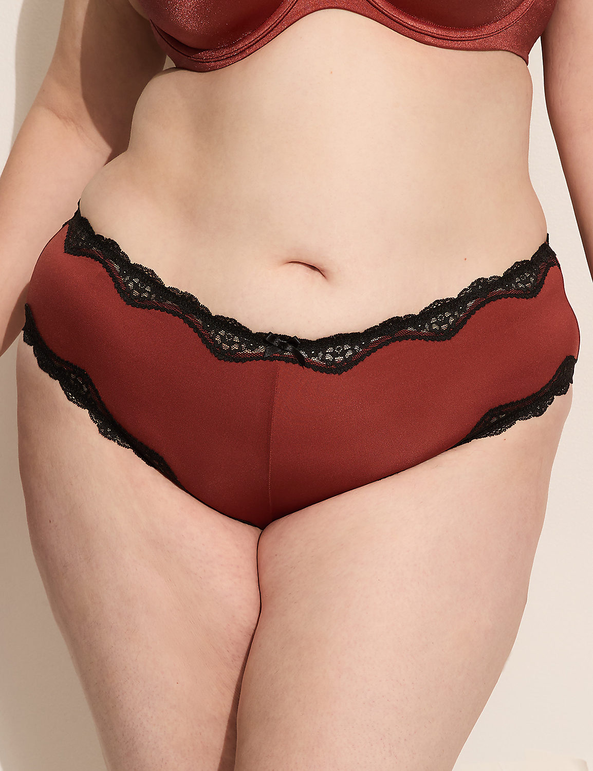 A person's torso is shown from the waist down, wearing rust-colored underwear with black lace trim, against a plain, light-colored background. Product Image 1