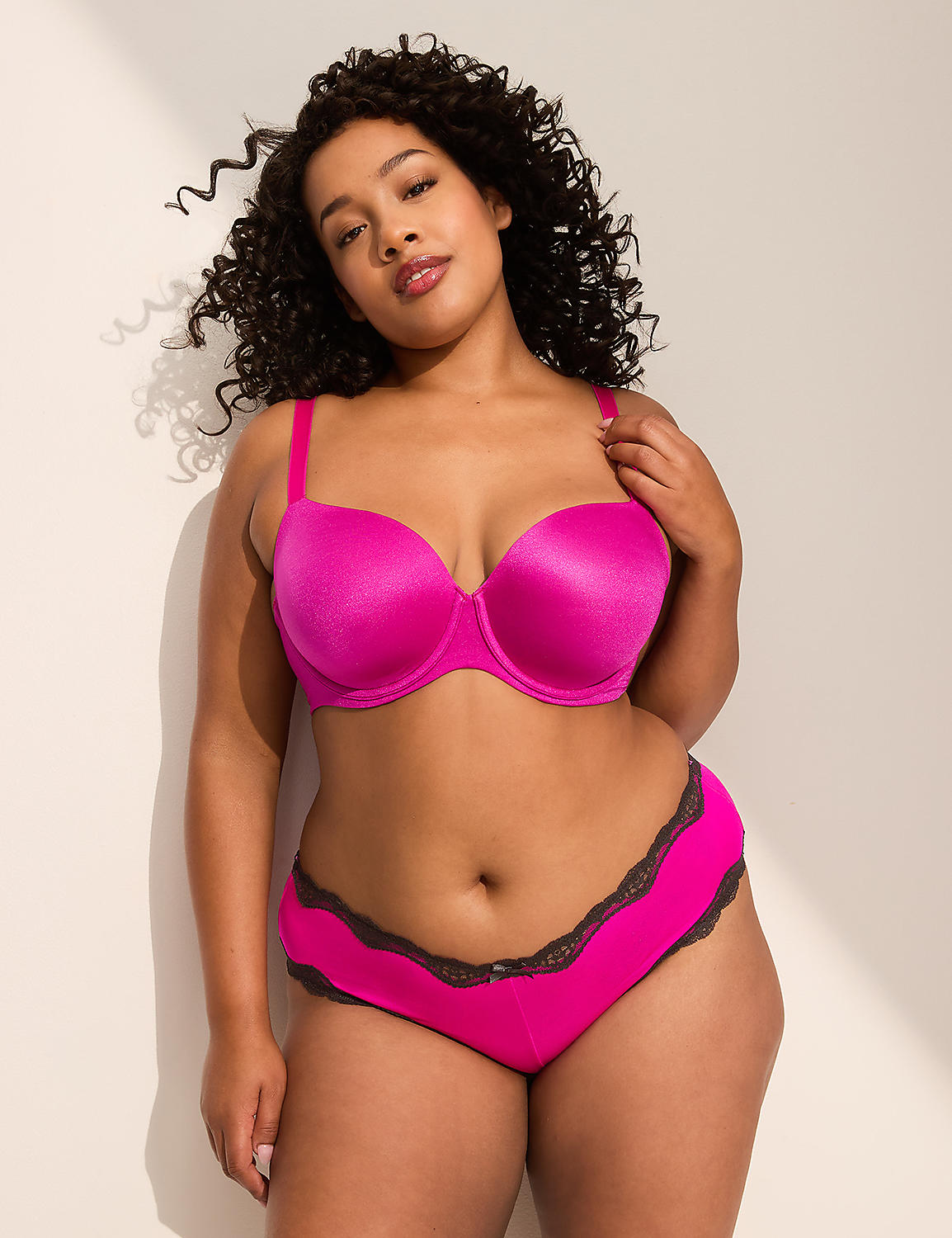 A woman in a bright pink bra and matching underwear stands against a plain, light-colored background with a shadow cast on the wall. Product Image 3
