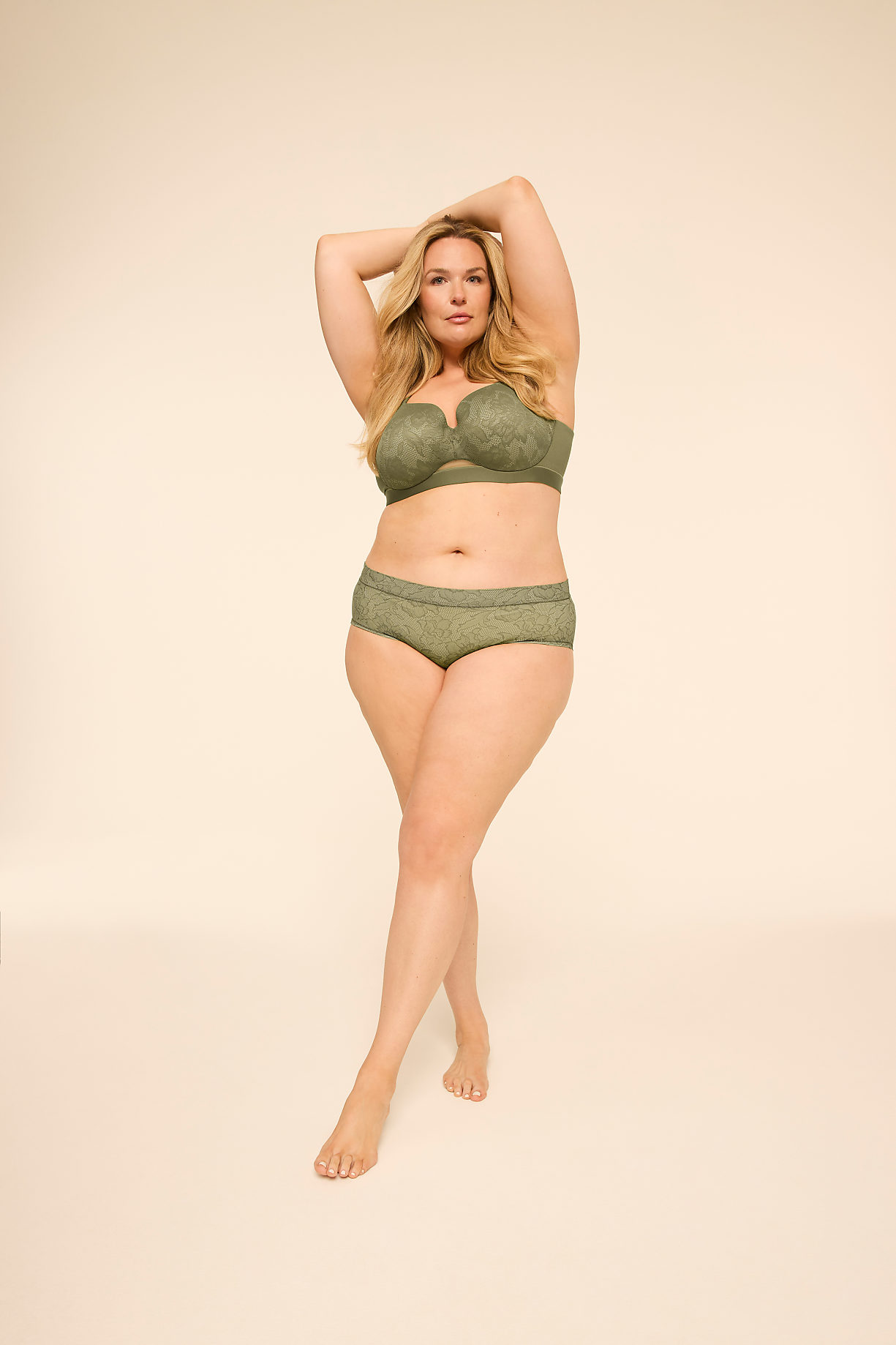 A woman in green lingerie poses with her arms raised against a plain, light-colored background. Product Image 6