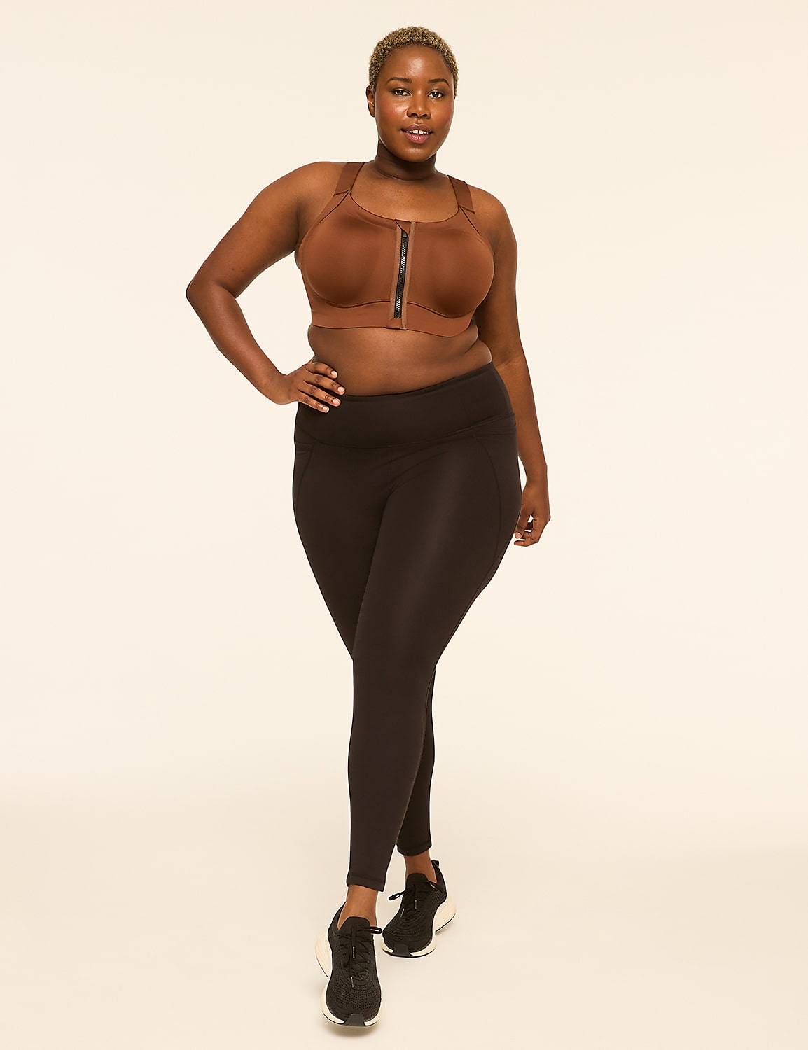 A woman in a brown sports bra and black leggings stands against a plain, light-colored background. Product Image 3