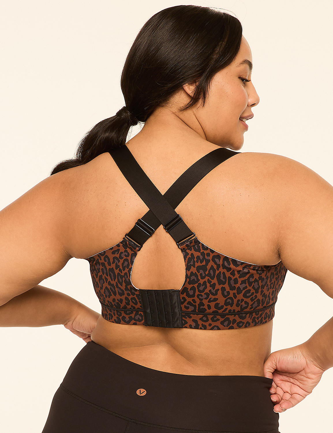 A woman with dark hair and a leopard print sports bra is shown from the back, with her hands on her hips, against a plain, light-colored background. Product Image 4
