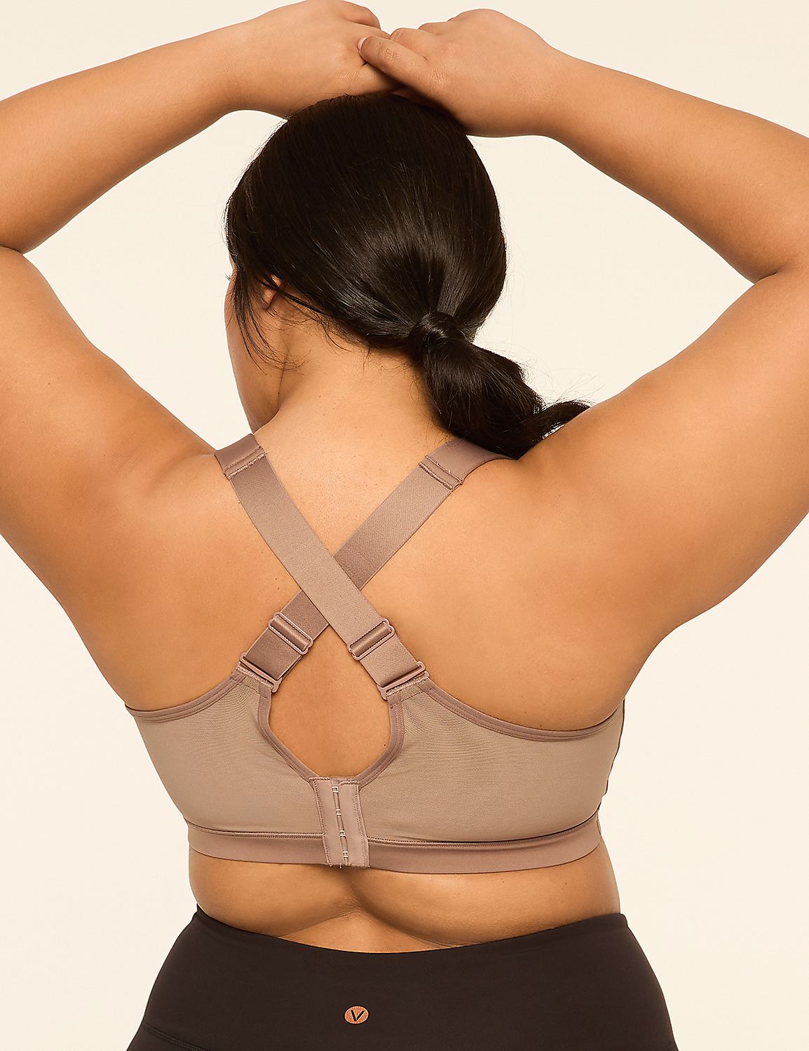 A woman's back is shown from the shoulders down, wearing a beige sports bra and black leggings, against a plain, light-colored background. Product Image 4