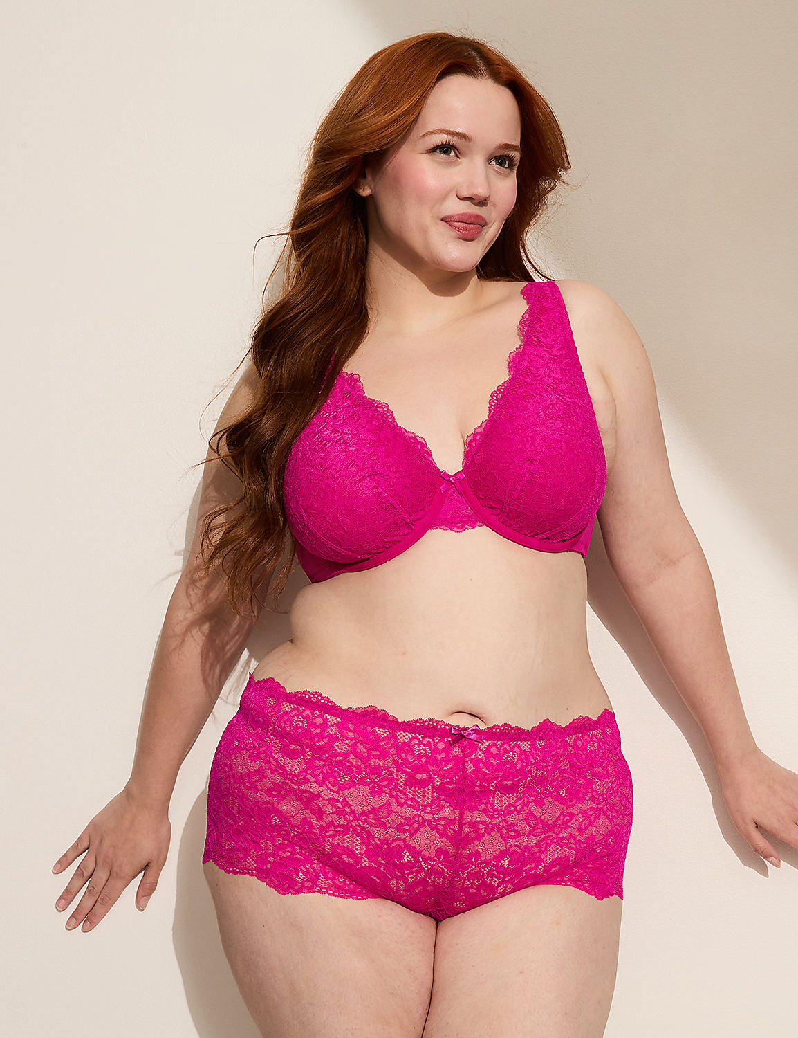 A woman with long red hair poses in a bright pink lace bra and matching shorts against a plain, light-colored background. Product Image 3