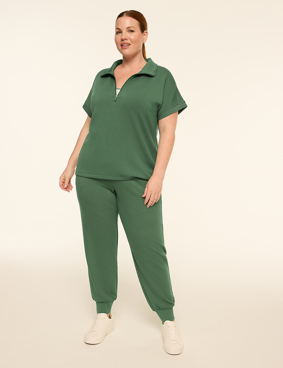 A woman in a green tracksuit stands against a plain, light-colored background. Product Image 3