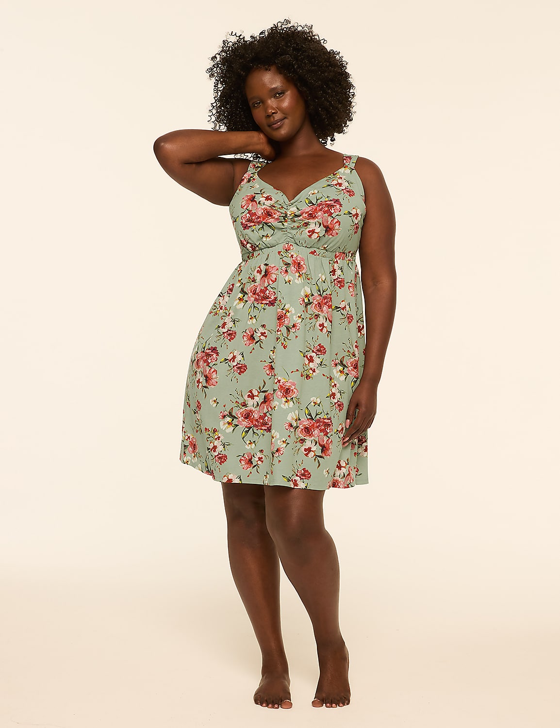 A woman in a floral dress stands against a plain, light-colored background. Product Image 1