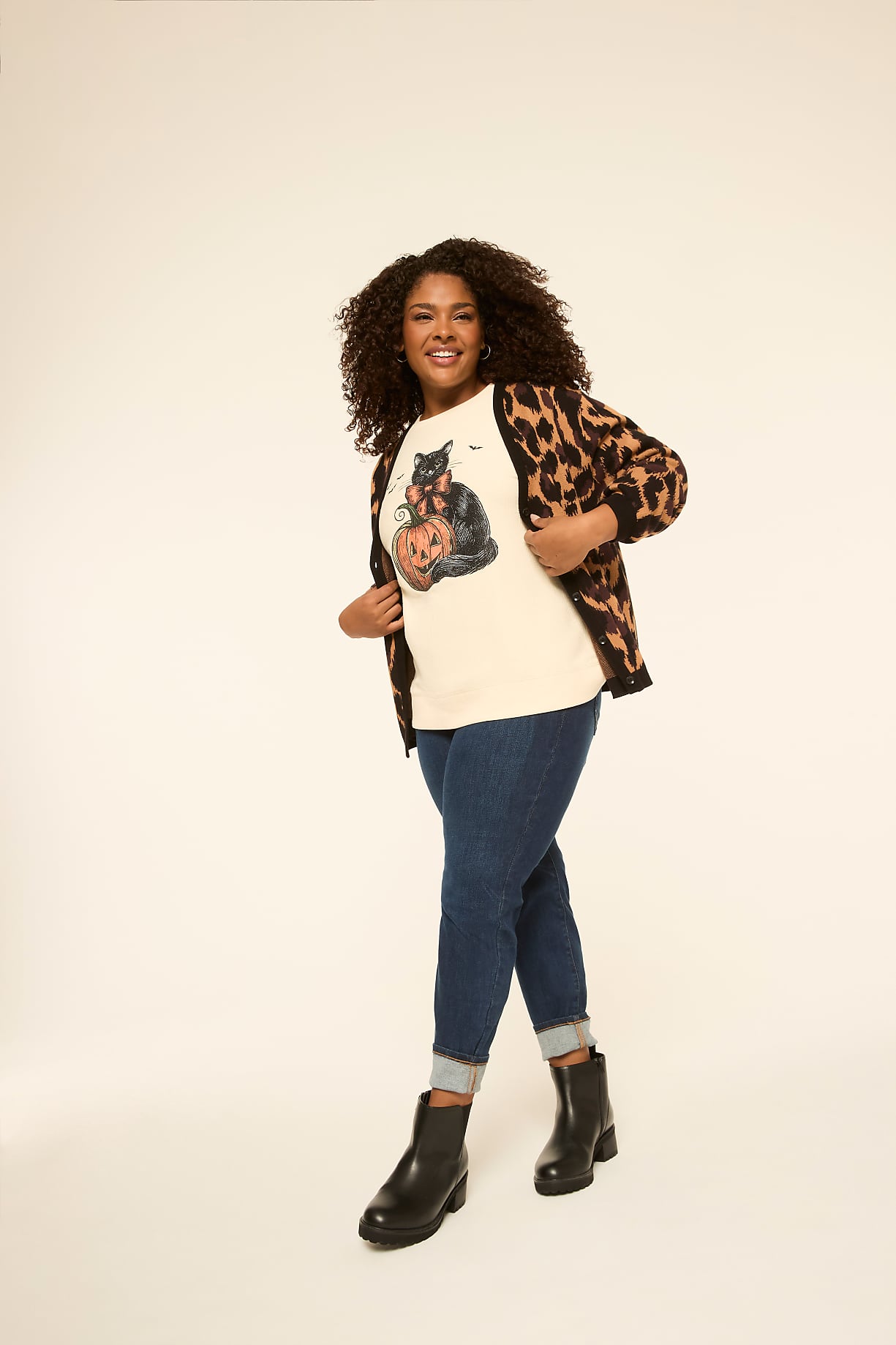 A smiling woman in a cat-themed sweater and leopard print cardigan stands against a plain, light-colored background. Product Image 6