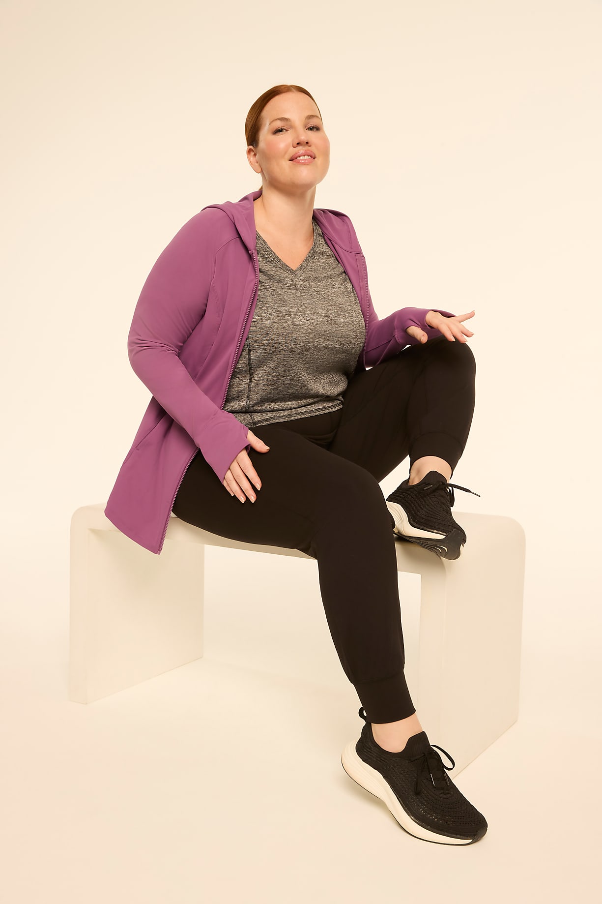 A woman in athletic wear sits on a white stool against a plain, light-colored background. Product Image 6