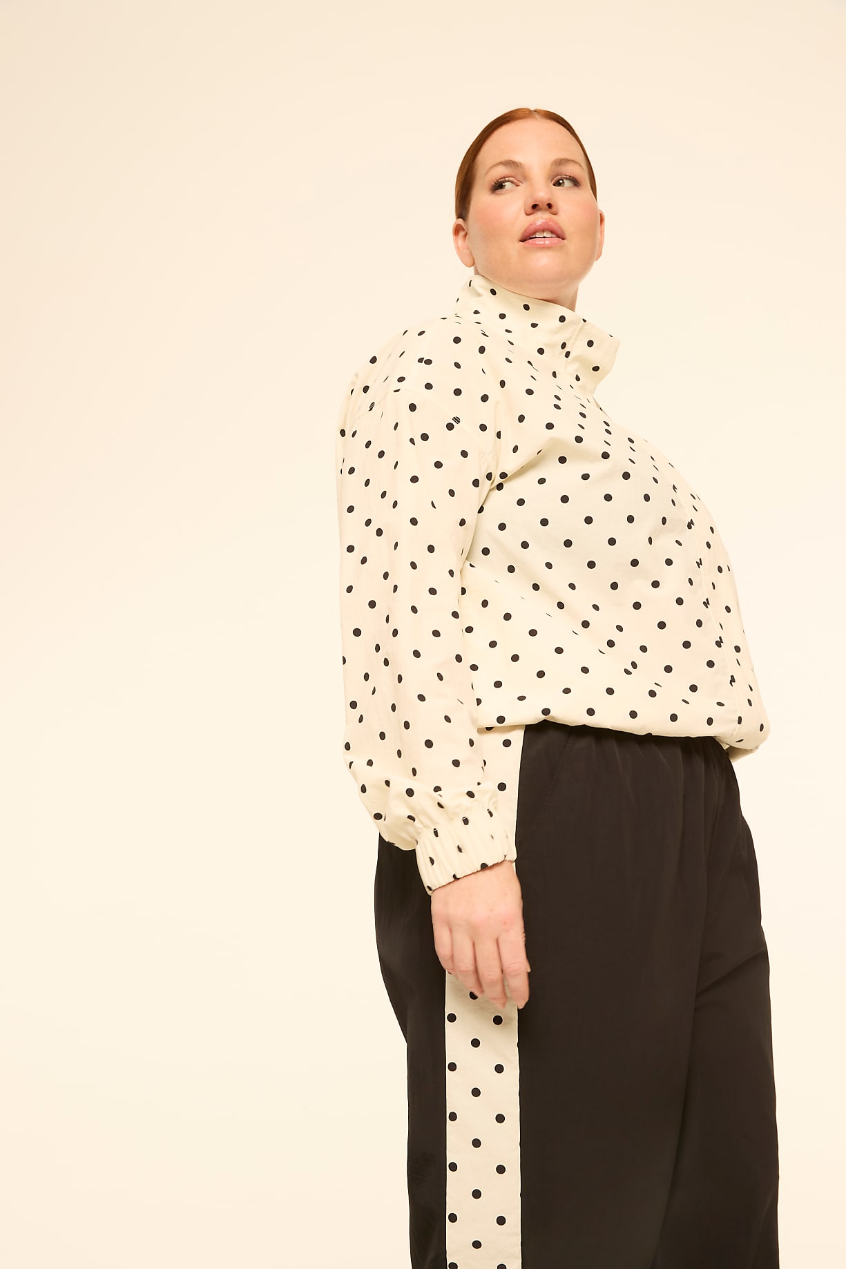 A woman in a polka dot blouse and black pants stands against a plain, light background. Product Image 6