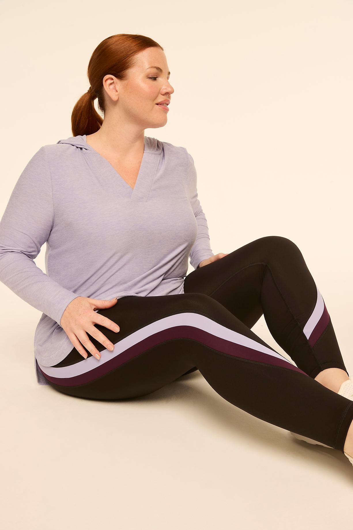 A woman in athletic wear sits on a plain background, her body angled to the side. Product Image 7