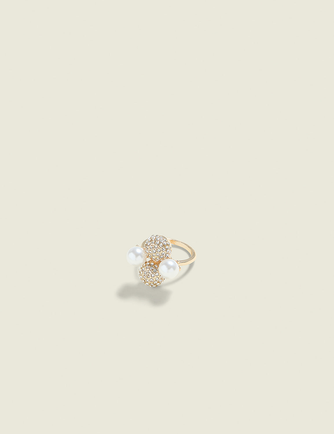 A gold ring with pearl and diamond accents rests on a plain, light-colored background. Product Image 1