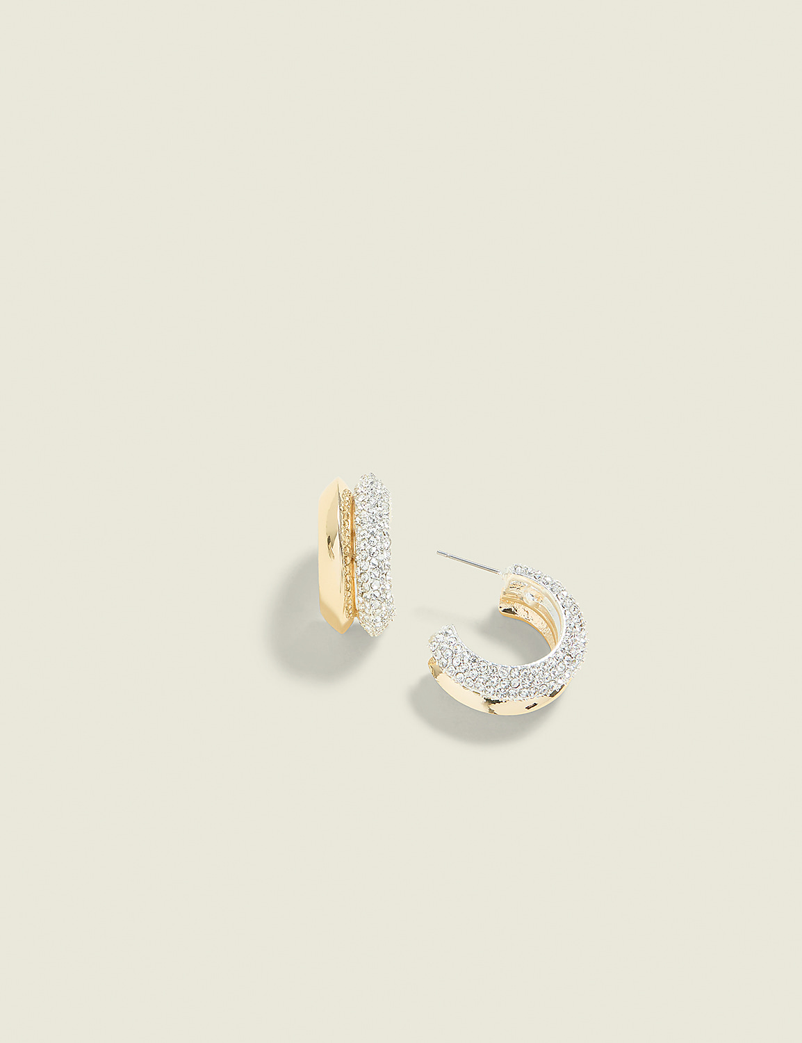 A pair of gold hoop earrings encrusted with small diamonds rests on a pale yellow background. Product Image 1