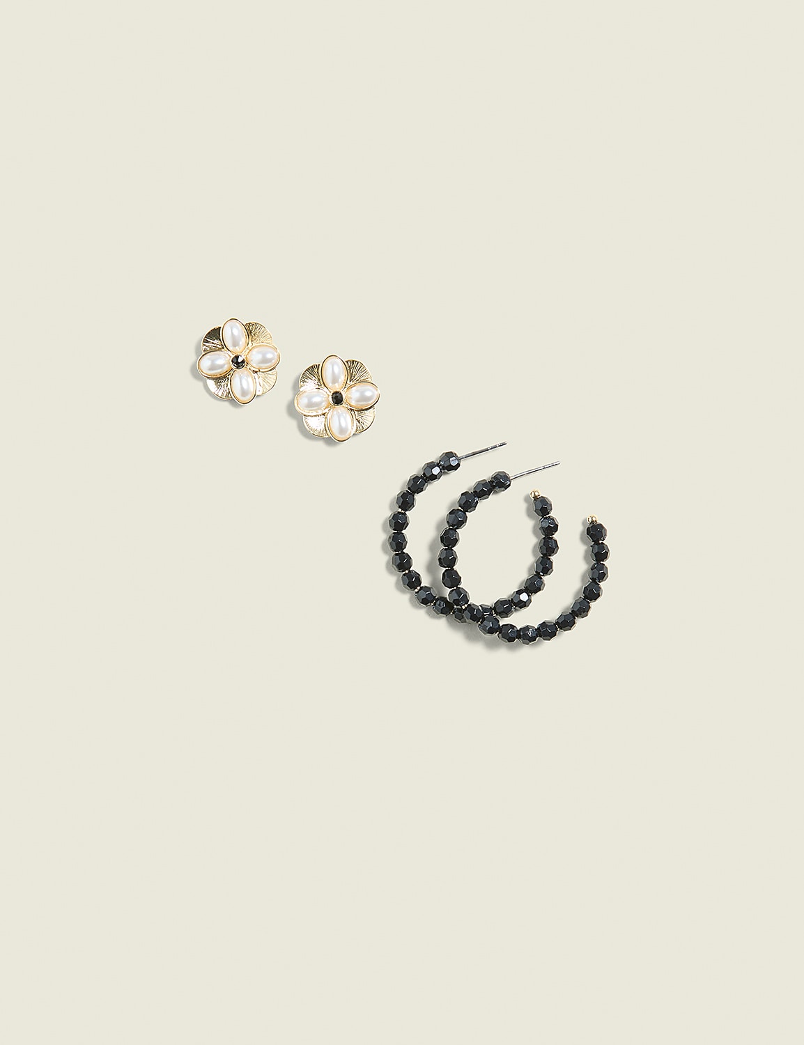 Two pairs of earrings, one floral with pearls and the other black beaded hoops, rest on a plain, light-colored background. Product Image 1
