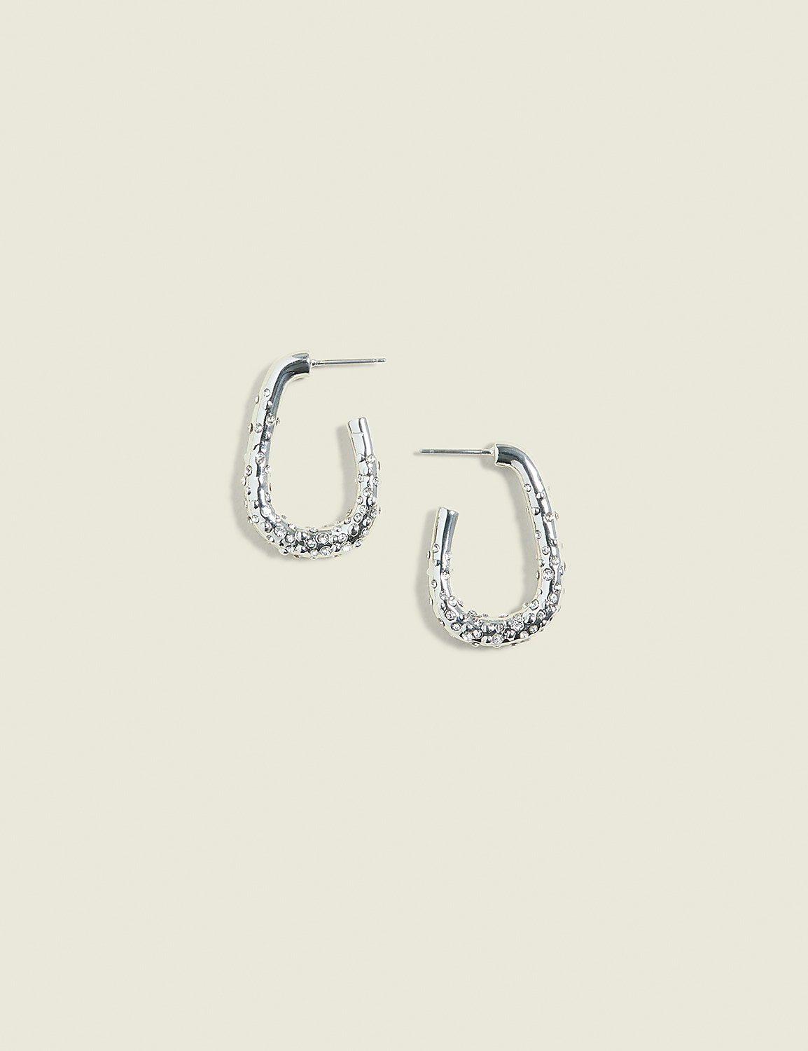 A pair of textured silver hoop earrings rests on a pale, textured background. Product Image 1