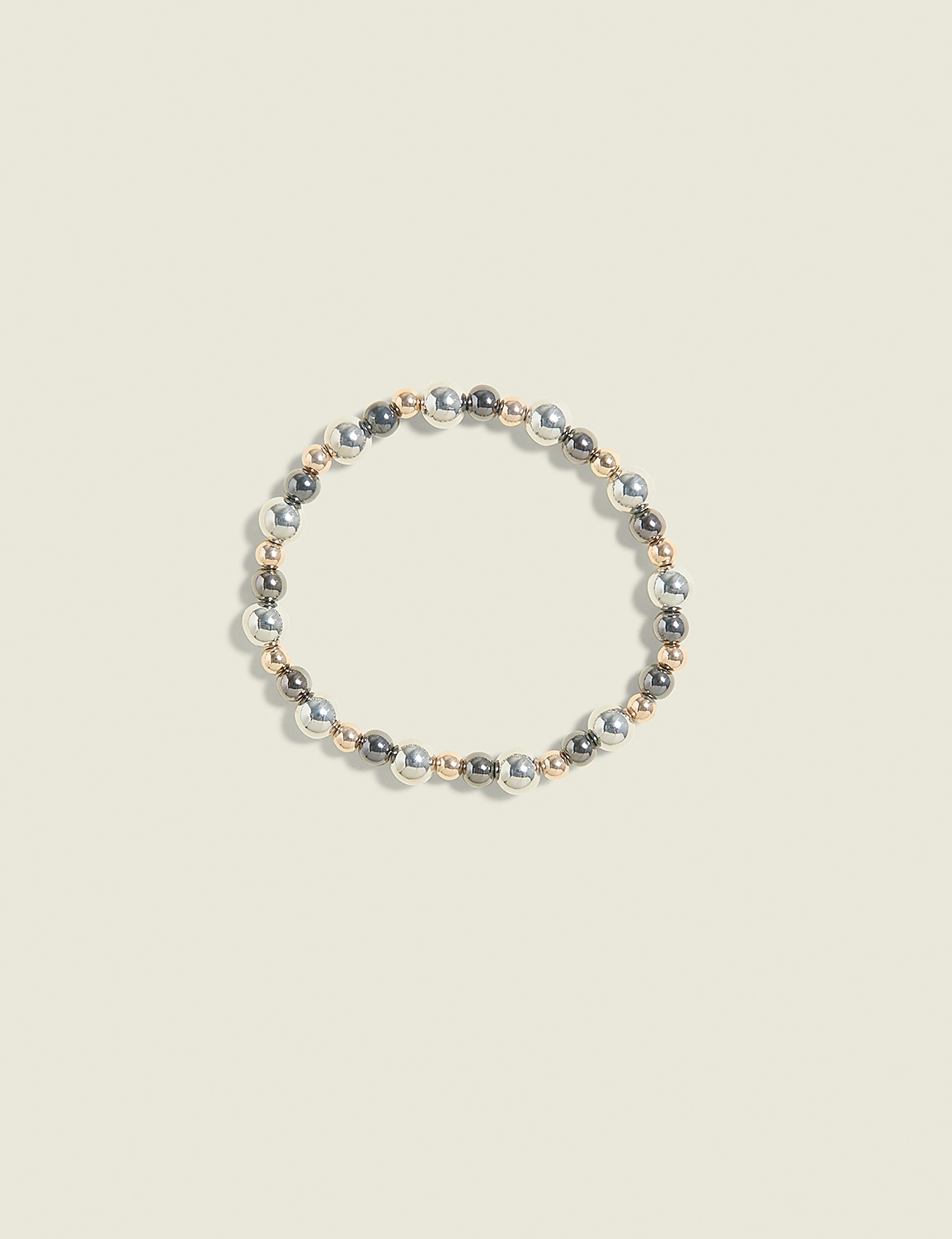 A bracelet of silver, gold, and gray beads is centered on a pale yellow background. Product Image 1