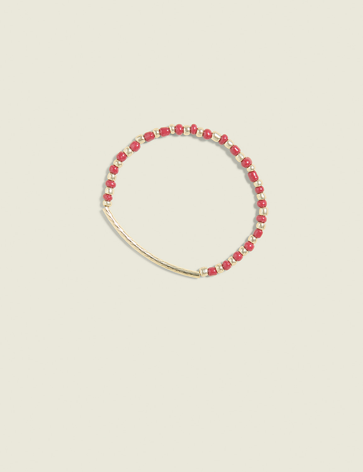 A delicate gold bar bracelet with red beads is centered against a soft, pale yellow background. Product Image 1