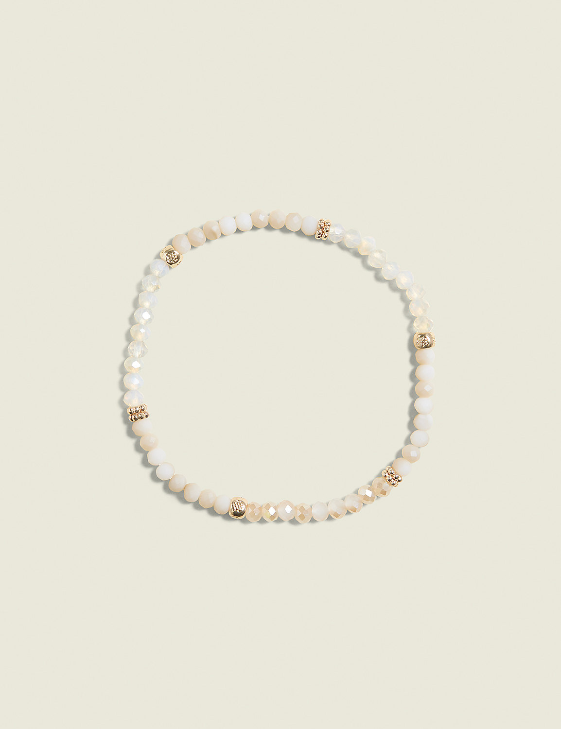 A delicate bracelet with cream-colored beads and gold accents rests on a pale, textured background. Product Image 1
