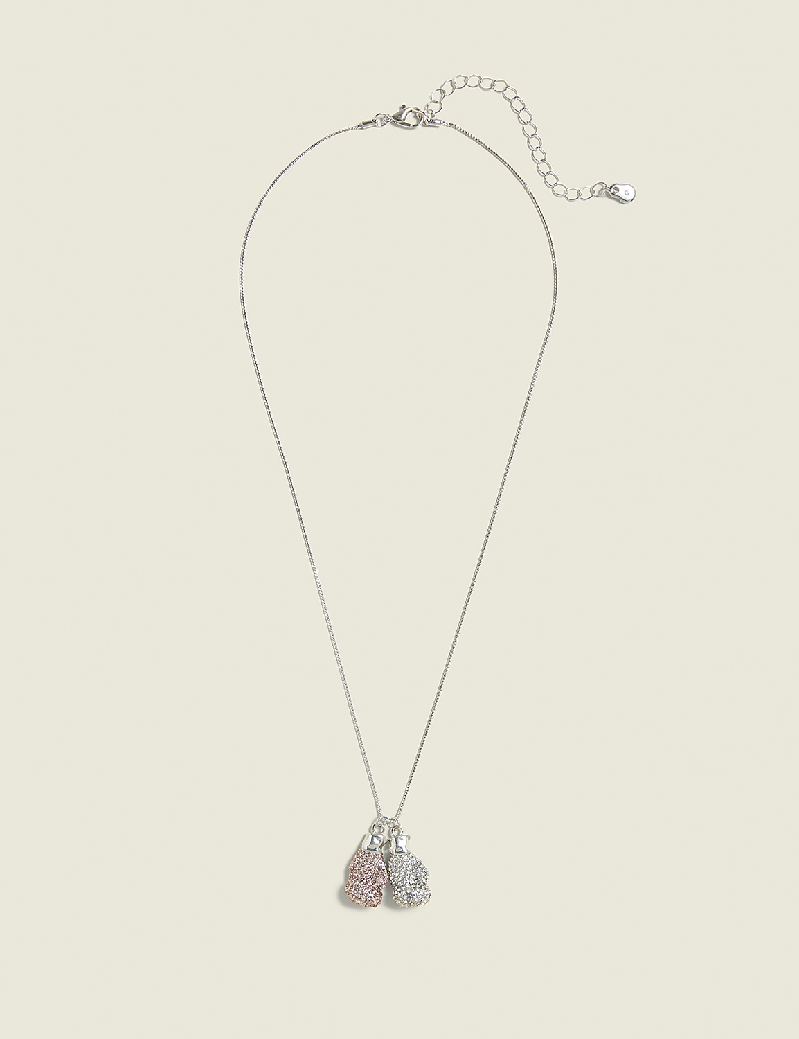 A delicate silver necklace with two small, sparkling boxing glove charms, one pink and one silver, hangs against a plain, light beige background. Product Image 1