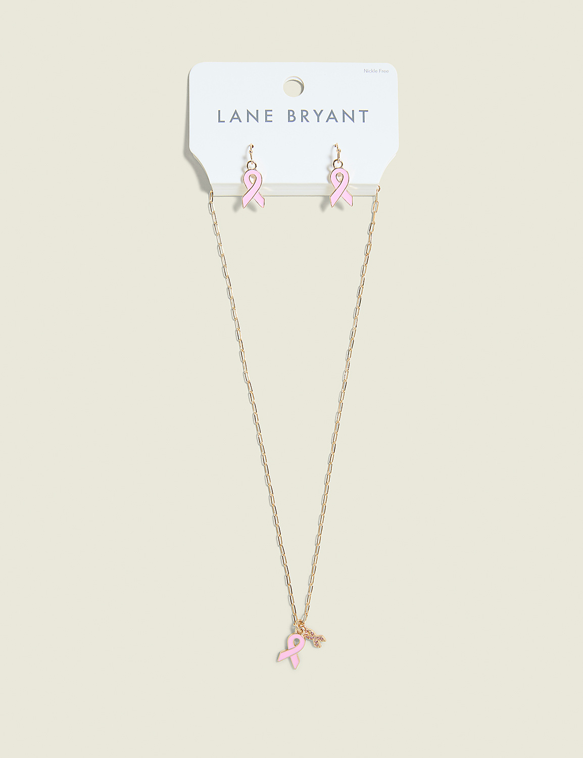 A gold necklace with a pink ribbon charm and matching pink ribbon earrings hang from a Lane Bryant card against a plain, light brown background. Product Image 1