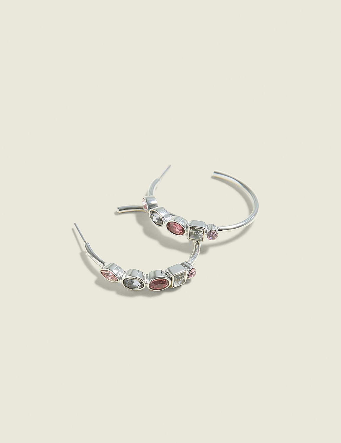 A pair of silver hoop earrings with colorful gemstones are displayed against a soft, light beige background. Product Image 1