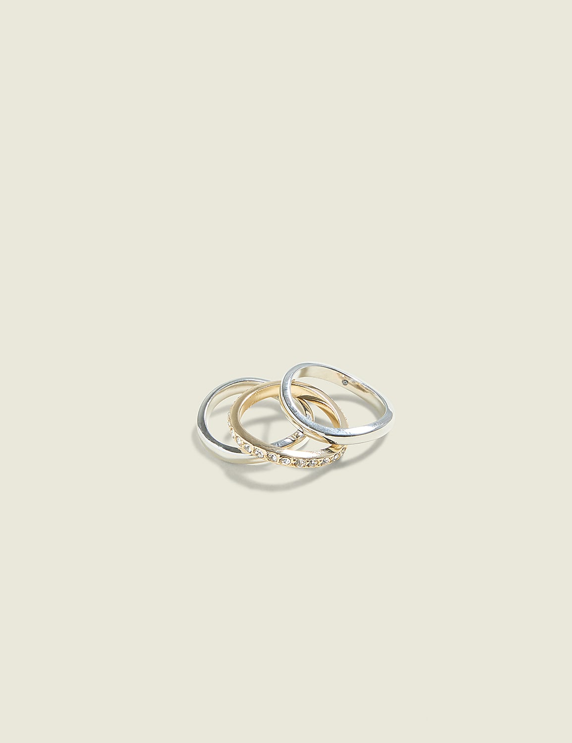 Three intertwined rings, one gold with small diamonds and two silver, rest on a plain, light beige background. Product Image 1