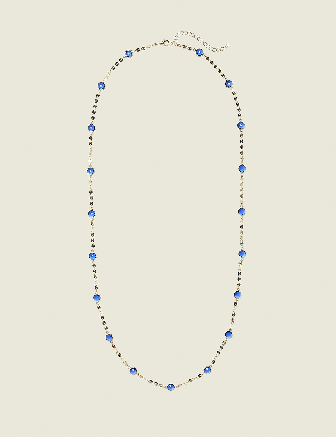 A delicate gold necklace with blue beads and small dark accents lies on a plain, light beige background. Product Image 1