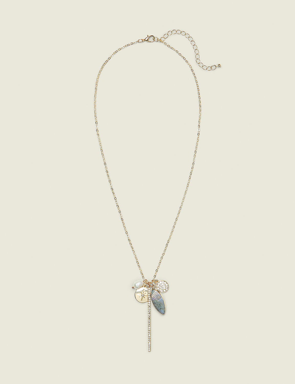A delicate gold chain necklace with multiple charms, including a coin and a grey stone, hangs against a plain, light beige background. Product Image 1